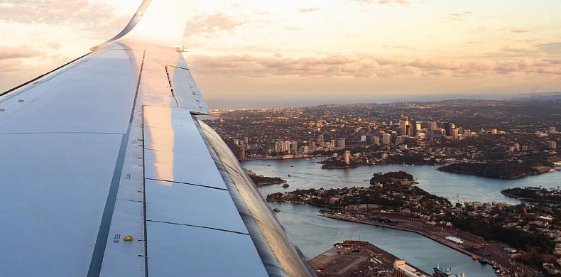 View of a person looking out of an airplane window overlooking a city.